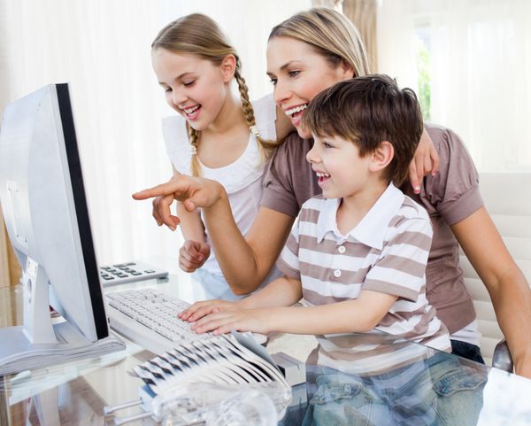 کودکان و مادرشان از کامپیوتر در خانه استفاده می کنند