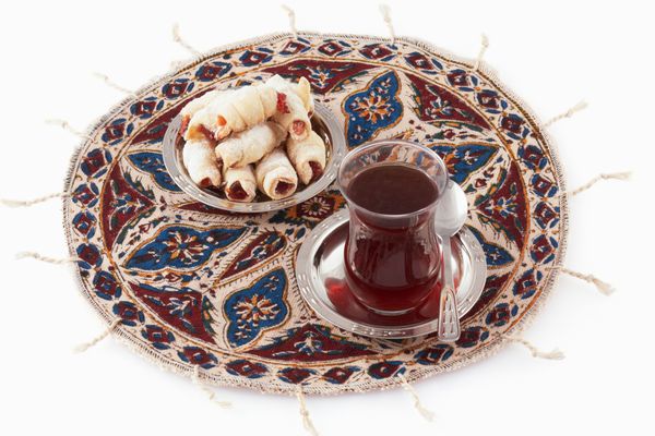 چای در لیوان سنتی شرقی اورمود و کلوچه روی پارچه کوچک - قلمکار ایرانی جدا شده روی سفید