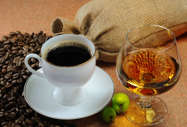 فنجان قهوه لیوان کنیاک و کیسه های دانه قهوه