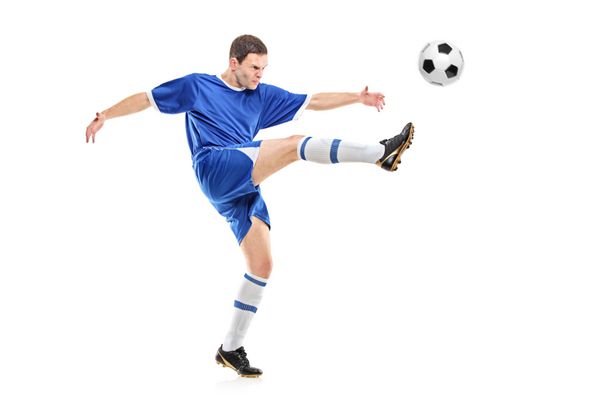 یک بازیکن فوتبال در حال شلیک به یک توپ جدا شده در پس زمینه سفید