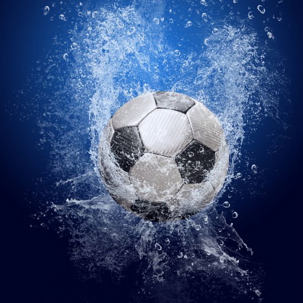 قطرات آب در اطراف توپ فوتبال در پس زمینه آبی