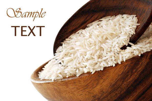 برنج نپخته در کاسه چوبی با قاشق روی زمینه سفید با فضای کپی ماکرو با دف کم عمق