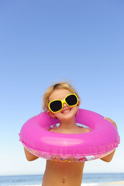 پرتره تابستانی کودک با عینک آفتابی و حلقه بادی در ساحل