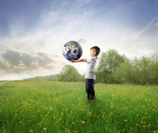 کودکی که زمین را روی یک چمنزار سبز نگه داشته است