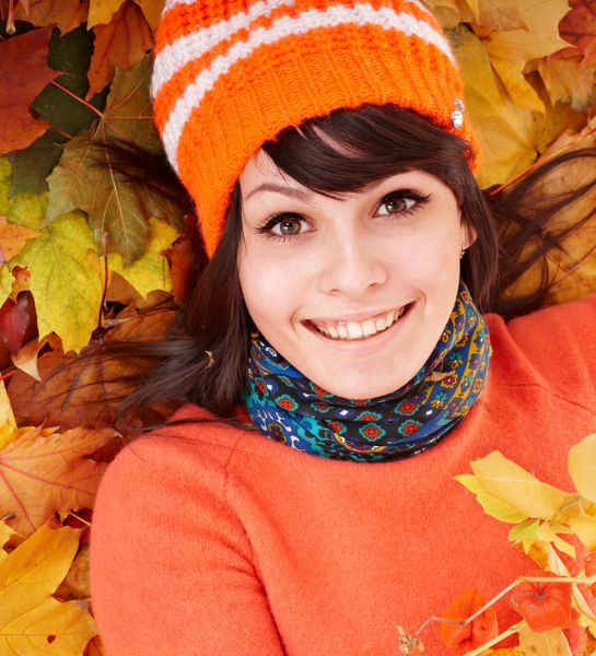 زن جوان در برگ های نارنجی پاییزی فضای باز