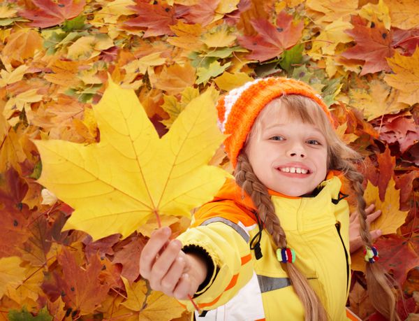 دختر کوچک در برگ های نارنجی پاییزی فضای باز