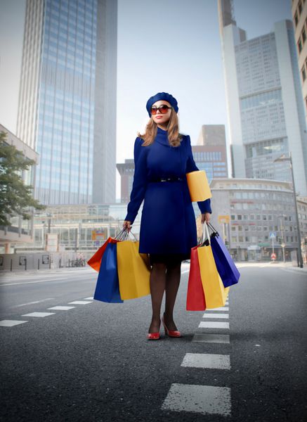 زنی در حال حمل چند کیسه خرید در یکی از خیابان های شهر