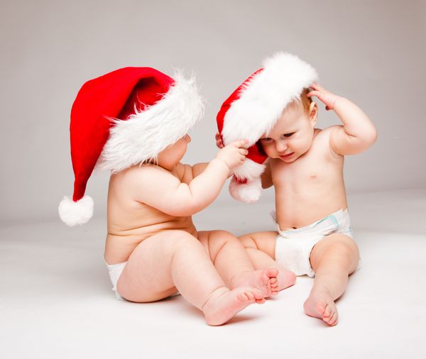 بچه در حال بیرون آوردن کلاه بابانوئل از سر دوستش