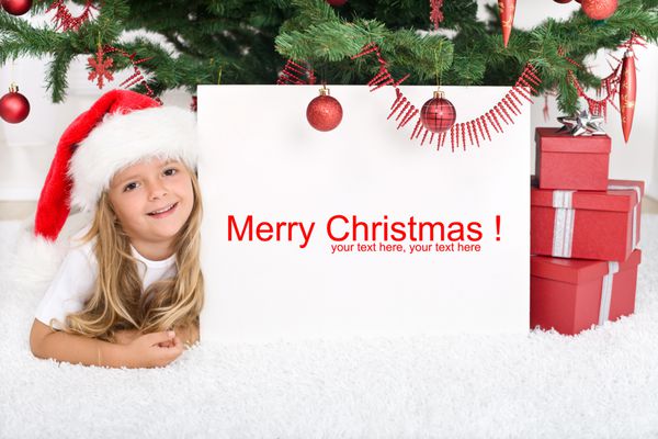 دختر کوچک دراز کشیده زیر درخت کریسمس با بنر برای متن
