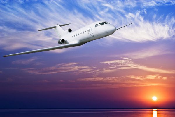 هواپیمای مسافربری در هنگام غروب خورشید بر فراز دریای استوایی پرواز می کند
