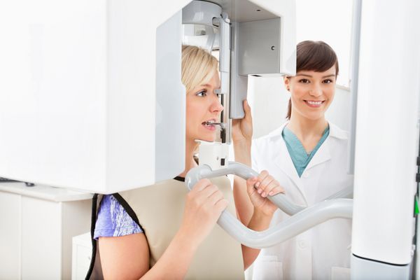 دندانپزشک جوانی که از دندان های بیمار عکسبرداری با اشعه ایکس دیجیتال پانوراما می گیرد