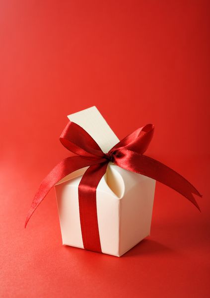 جعبه هدیه با برچسب خالی که با پاپیون روبان قرمز بسته شده است