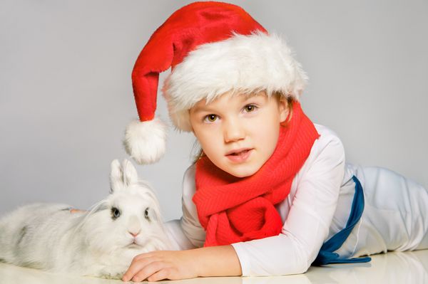 پرتره پسر کوچک زیبا در لباس سال نو با اسم حیوان دست اموز سفید