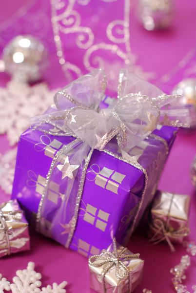 جعبه هدیه کریسمس به رنگ بنفش با روبان نقره ای در زمینه صورتی