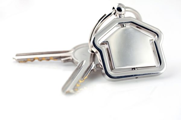 نمای ماکرو دو کلید نقره‌ای با شکل خانه در پس‌زمینه سفید