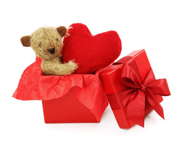 خرس عروسکی با قلب در جعبه هدیه جدا شده در پس زمینه سفید