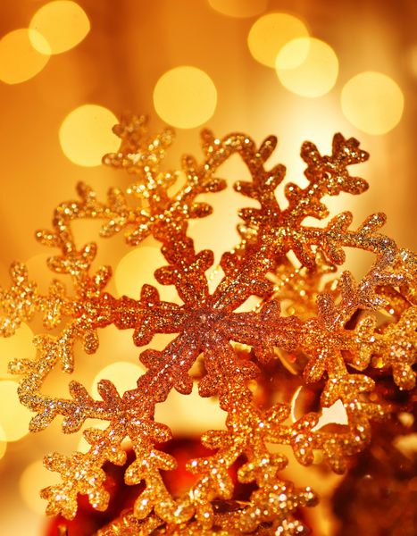 تزیین درخت کریسمس طلایی پس‌زمینه دانه‌های برف و تزئینات تعطیلات روی چراغ‌های فوکوس انتزاعی