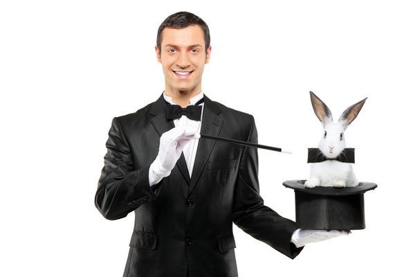شعبده‌بازی با کت و شلوار مشکی که کلاه بالایی با خرگوش در دست دارد و روی پس‌زمینه سفید جدا شده است