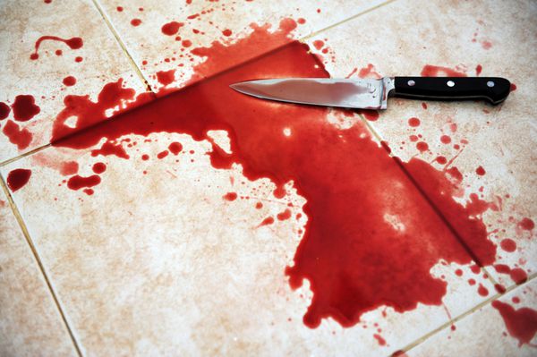 تصویر مفهومی از یک چاقوی تیز با خون روی آن که روی کاشی‌های روی زمین قرار گرفته است