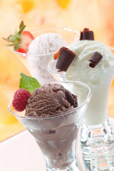 نمای نزدیک از بستنی خوشمزه وانیلی توت فرنگی و شکلاتی با انواع توت های تازه نعناع و شکلات