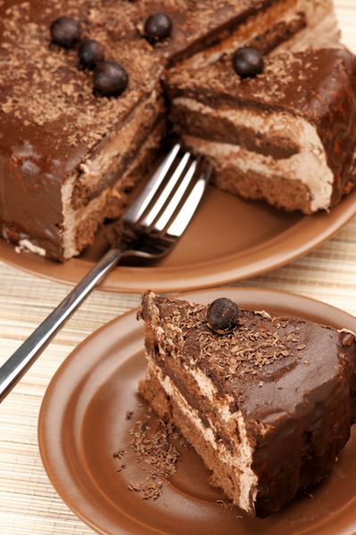نمای نزدیک از کیک شکلاتی خانگی و چنگال روی حصیر بژ
