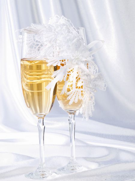 لیوان هایی با شامپاین و جوراب عروس روی یک ابریشم سفید