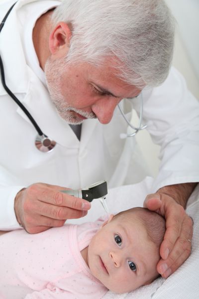 متخصص اطفال در حال معاینه گوش نوزاد