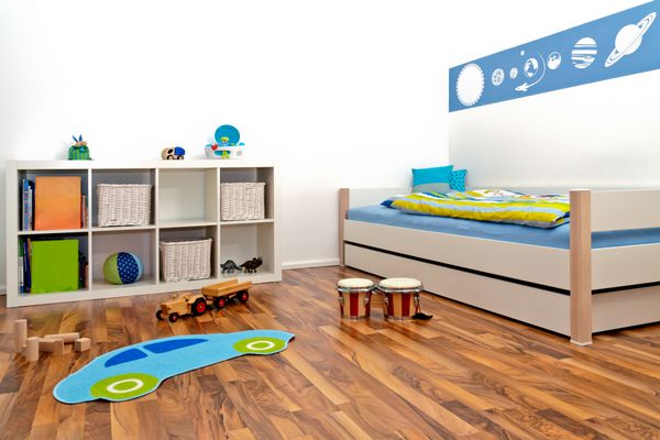 اتاق بازی کودکان با تخت و قفسه و تعدادی اسباب بازی