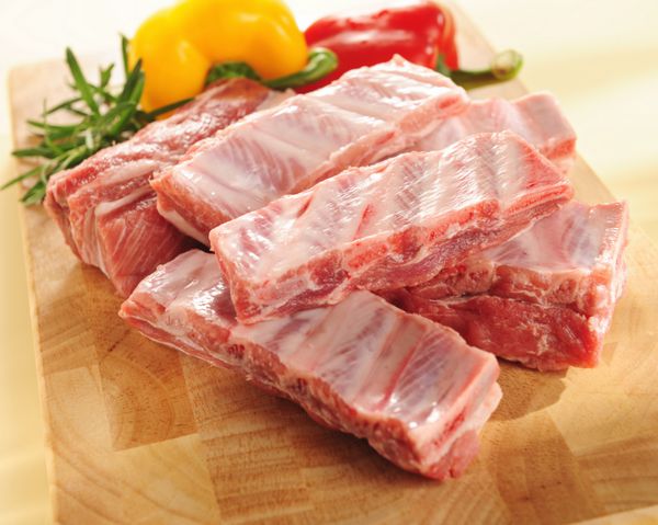 دنده های گوشت خوک خام روی تخته برش و سبزیجات