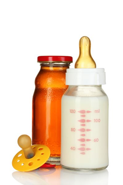 آب میوه شیشه شیر کودک و پستانک جدا شده روی سفید