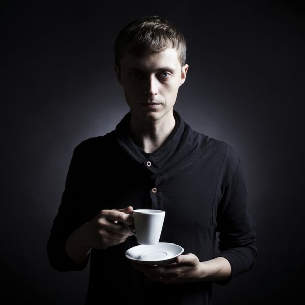 مرد جوان با فنجان قهوه در دستانش