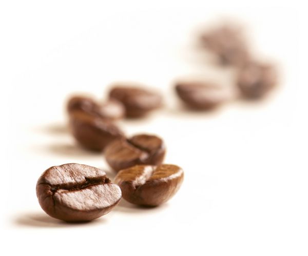 دانه های قهوه یک خط زیگزاگ جدا شده روی سفید می کشند تمرکز نرم