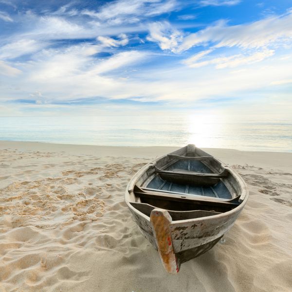 قایق در ساحل هنگام طلوع آفتاب