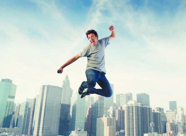 مردی شاد در حال پریدن با منظره شهری در پس‌زمینه