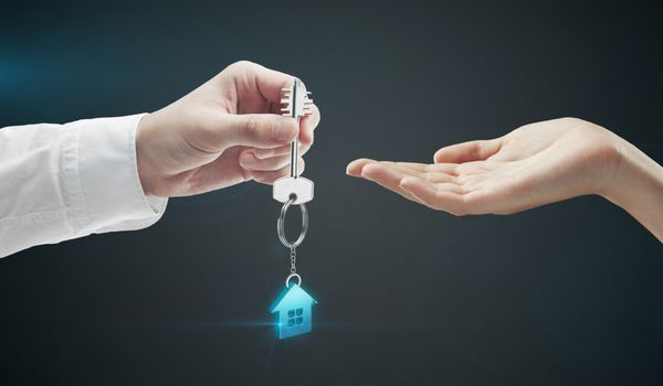 مرد کلید خانه را به زن می دهد کلید با دسته کلید به شکل خانه روی زمینه مشکی