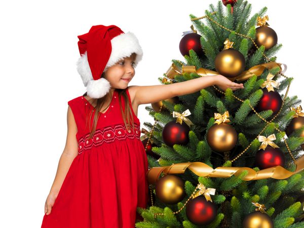 دختر کوچک زیبا با هدیه در نزدیکی درخت کریسمس لبخند می زند