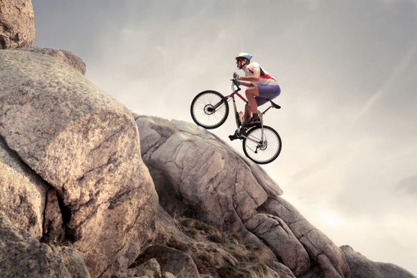 دوچرخه سوار در حال بالا رفتن از صخره