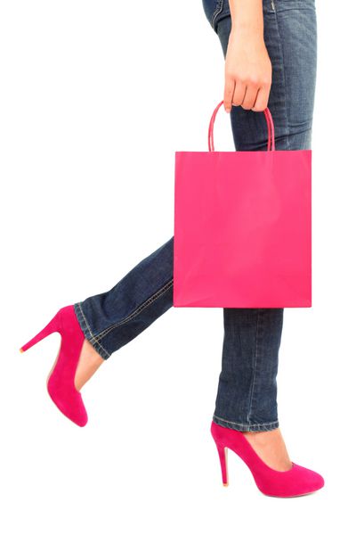 مفهوم خرید کیف خرید شلوار جین و کفش پاشنه بلند با فضای کپی روی کیف خرید نمای نزدیک زن خریدار جدا شده روی پس‌زمینه سفید صورتی
