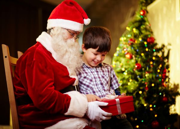 عکس پسر ناز و بابانوئل که جعبه کادو را در دست دارند و به آن نگاه می کنند