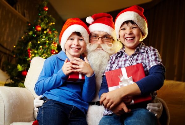 عکس پسرهای شاد که کادو در دست دارند و بابانوئل بین آنها