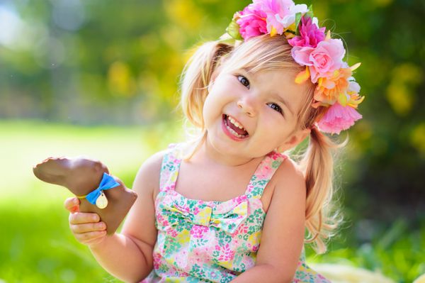 دختر بچه عید پاک با اسم حیوان دست اموز شکلاتی در فضای باز در باغ سبز