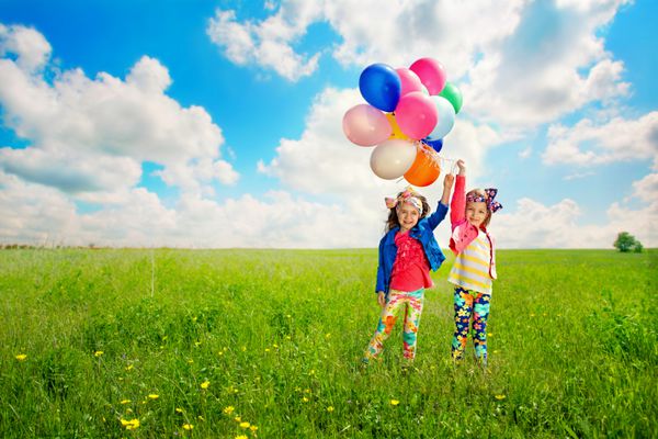کودکان شاد ناز با بادکنک هایی که در زمین بهار راه می روند شادی دوستی مفهوم مد روز