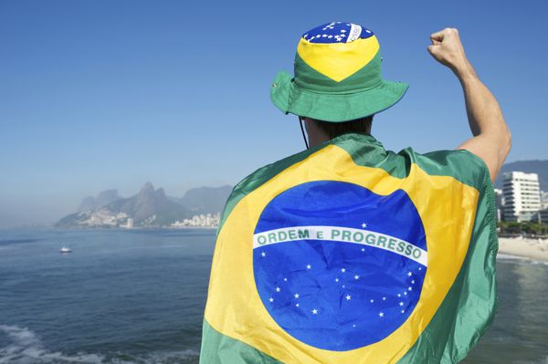بازیکن فوتبال برزیلی با پرچم و کلاه در مقابل خط افق شهر ساحل ایپانما ریودوژانیرو برزیل
