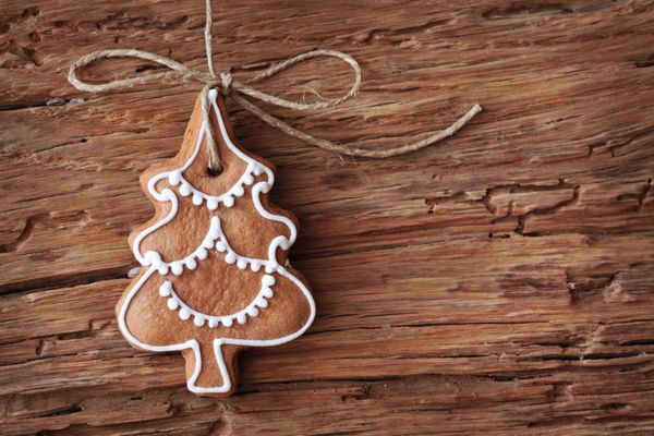 درخت کریسمس شیرینی زنجفیلی که روی پس زمینه چوبی آویزان شده است