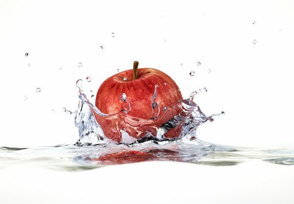 پاشیدن سیب قرمز در آب نمای جانبی نزدیک با عمق میدان رندر دیجیتال سه بعدی در پس زمینه سفید