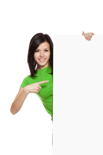 زن جوان لبخند شاد ایستاده ایستاده و انگشت خود را به سمت تخته خالی نشانه می گیرد دختری جذاب پیراهن سبز می پوشد جدا شده روی پس زمینه سفید عکسبرداری استودیویی