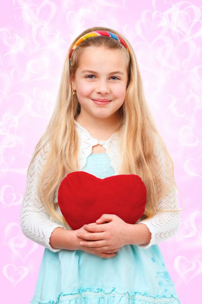 دختر جوانی که یک قلب قرمز در دست دارد