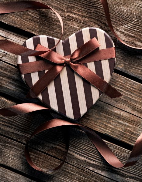 جعبه هدیه روز ولنتاین به شکل قلب با روبان منحنی روی چوب قدیمی پس زمینه تعطیلات قدیمی