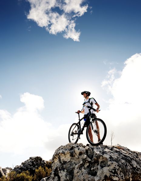 دوچرخه سوار مطمئن کوهستانی ایستاده و در حال مشاهده منظره است