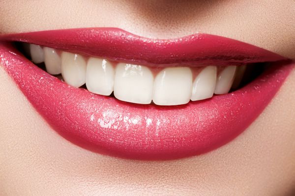لبخند زنانه شاد از نمای نزدیک با دندان های سفید سالم آرایش لب های سرخابی روشن زیبایی دندانپزشکی و مراقبت های زیبایی ماکرو دهان خندان زن
